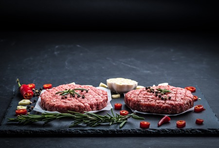 Raw cutlet of minced meat with ingredients on a dark cooking backgroundの写真素材