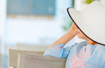 Smiling girl in a pretty white hat and light blue blouse looking awayの写真素材