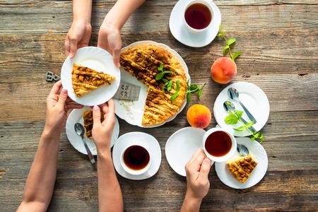 Friends Tea Party with amazing peach pie, big peaches, mint on the wooden table. Top view.の写真素材