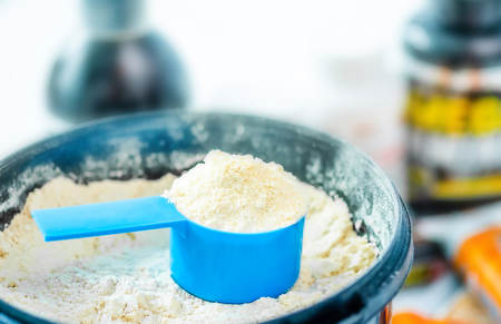 Closeup blue measure dish in bucket filled with sport protein powderの写真素材