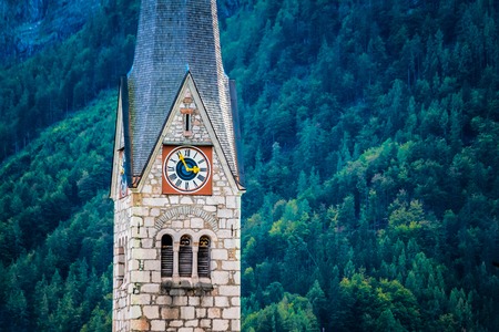 protestant churchs clock on high tower on th background of mountains in Hallstatt, Austria