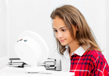 Teenage girl udergoes eye survey in ophthalmologic clinic with diagnostics deviceの写真素材