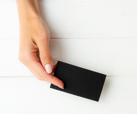 Woman holding black business card in hand. Tamplate for your design.の写真素材