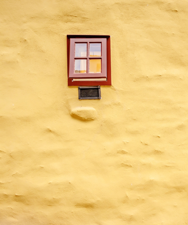 Small brown window on the big yellow masonry wallの写真素材