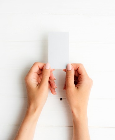 Woman holding white business card in hands. Tamplate for your design.の写真素材