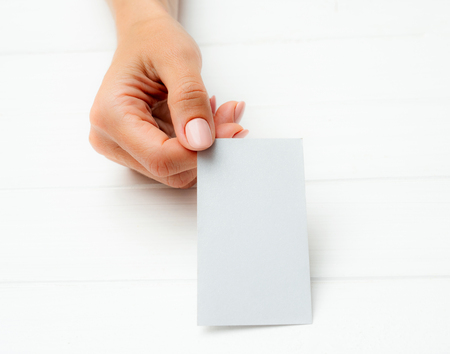 Woman holding white business card in hand. Tamplate for your design.の写真素材