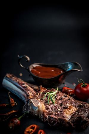 Grilled beef fillet on bbq with rosemary, pepper and savoury sauce on the dark cookind boardの写真素材