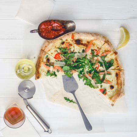 Part of seafood pizza with drink and slice of lemon on white wood tableの写真素材