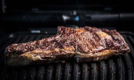 Big and juicy piece of beef steak on a grill seasoned with spices. Homemade bone-in rib eye beef steak. Piece of grilled BBQ on the grillの写真素材