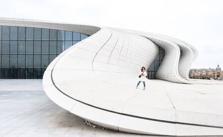 Baku, Azerbaijan - January 01, 2018: Girl in white clothes standing on the white curved wall of modern Heydar Aliev Center, Baku, Azerbaijanのeditorial素材