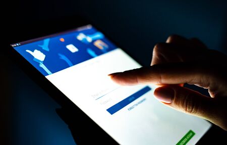 Kharkiv, Ukraine - 12 November 2018: close up girl hand using tablet with Facebook app log in on the...