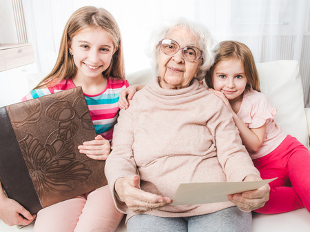 Smiling grandmother with granddaughters looking old photos togetherの写真素材