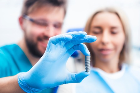 Dentist showing gray implant model to patient