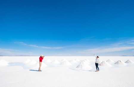 Tourists taking photos at sault banks on background of sunshine Salar de Uyuniの写真素材