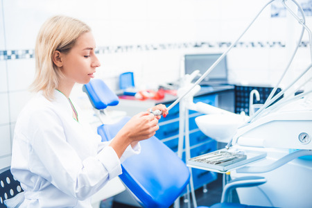 Dental doctor in white uniform working with equipment in stomathology officeの写真素材