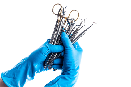 Closeup of hands in blue gloves holding dental equipment isolated on whiteの写真素材