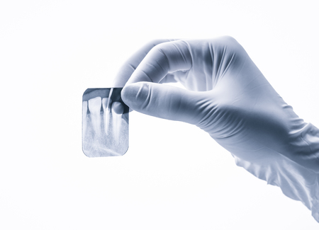 Closeup of hand in white glove holding small dental x-ray isolated on white