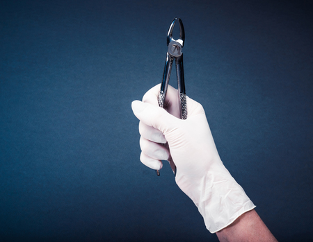 Hand in glove holding medical flatters on dark blue
