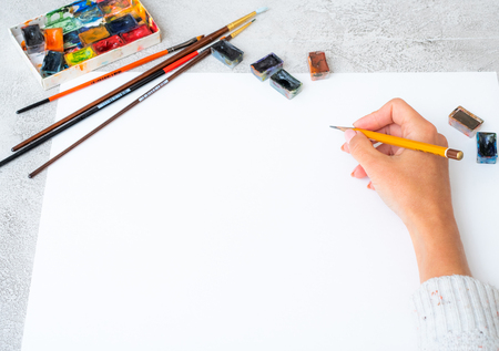 Top view of girl's hand drawing with pencils and paintsの写真素材