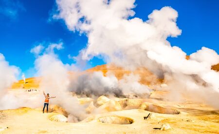 Girl near huge steaming geysers in sunshine Boliviaの写真素材