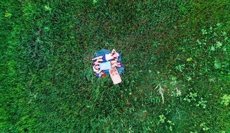 two little girls have a picnic with pizza on a green grass, aerial top viewの写真素材