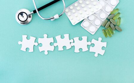 Puzzle pieces in row for lettering next to pills and phonendoscopeの写真素材