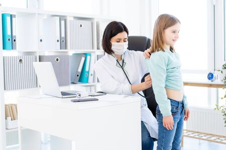 Nice doctor listening to little girl with phonendoscopeの写真素材