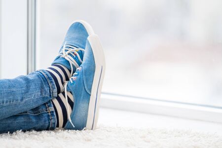 Legs in striped socks and blue gumshoes indoorsの写真素材