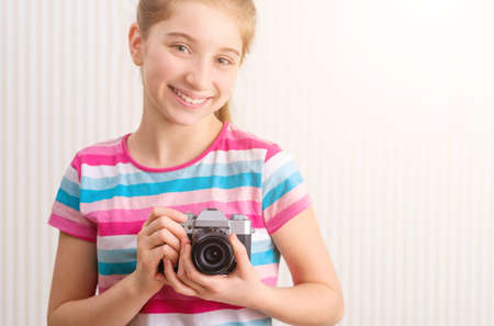Happy girl holding photo camera in studioの写真素材