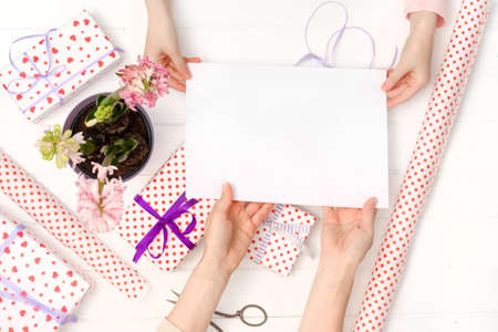 Mother and daughter holding blank sheet of paper A4 for design with giftsの写真素材
