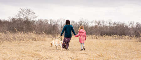 Back view of mother and daughter with dog