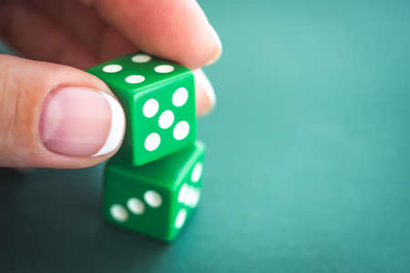 Girl gambling dice on green felt poker table, close up viewの写真素材