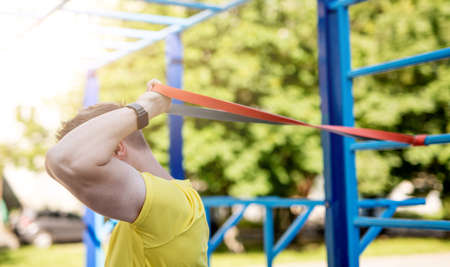 Man using resistance rubber band for fitness in sunny park