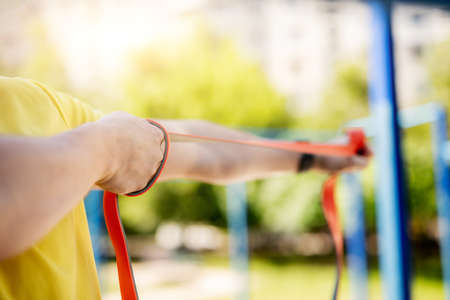 Man exercising with resistance rubber band in street, close up