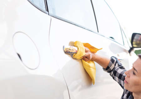 Girl polishing car door handle with microfiber cloth, close up