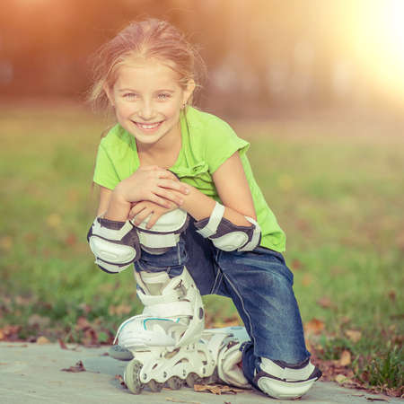 Cute little girl on roller skates sitting in parkの写真素材