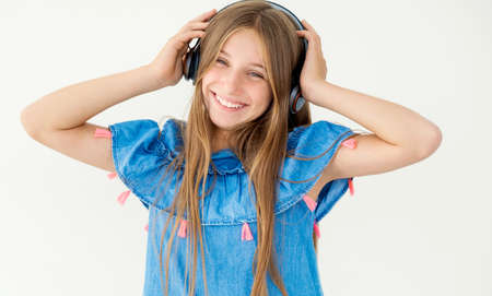 Pretty girl holding headphones on her head, isolated on white backgroundの写真素材