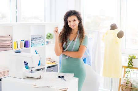 Confident sempstress in workshop with sewing equipmentの写真素材