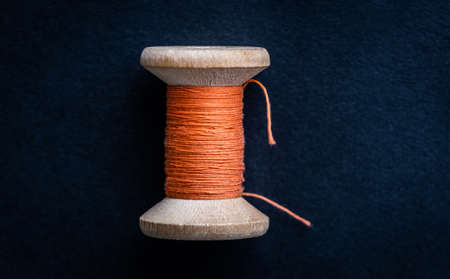 Close up view of orange retro thread on wooden bobbinの写真素材