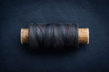 Spool of retro dark thread lying on dark backgroundの写真素材