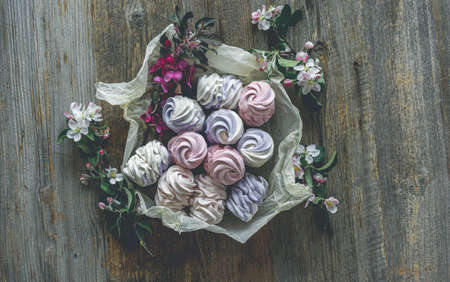 Delicious marshmallow on craft paper with spring flowers, top viewの写真素材