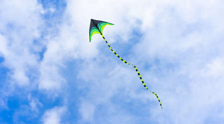 Colorful kite flying through air on sky backgroundの写真素材