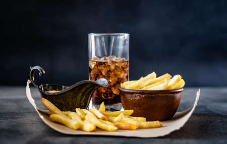 Delicious french fries near sauce boat and glass of beverageの写真素材