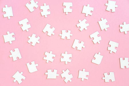 Background of of white jigsaw puzzle pieces on pink, top viewの写真素材