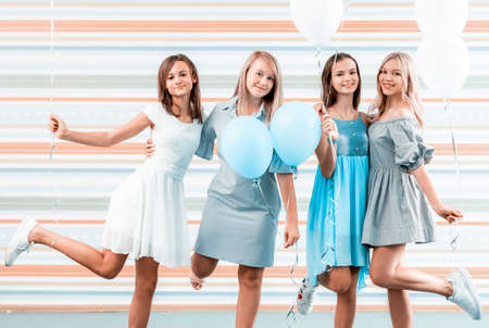 Beautiful girls in dresses holding balloons on striped backgroundの写真素材