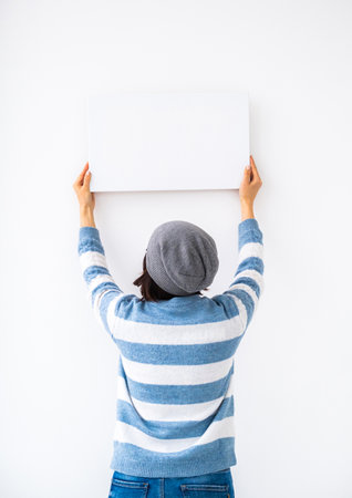 Girl holding blank canvas on white wallの写真素材