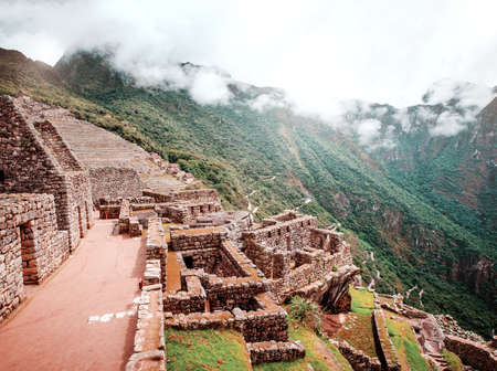 Sunshine breathtaking view of Machu Picchu stone anchient walls and temple among mountains covered...