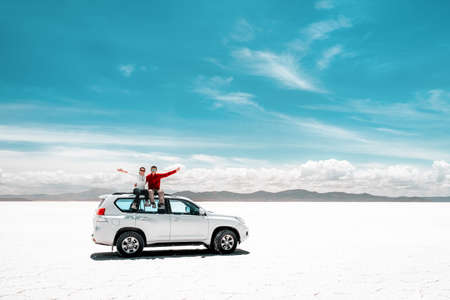 Pair of tourists sitting on white car in Salar de Uyuniの写真素材