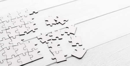 Pieces of empty jigsaw puzzle on white tableの写真素材
