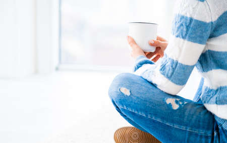 Girl relaxing near window with cup of tea indoorsの写真素材